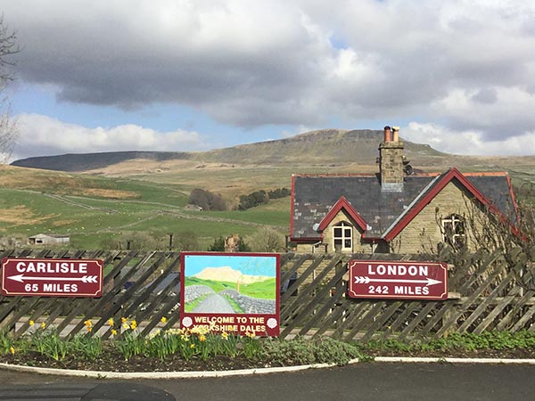 Signage at Horton-in-Ribblesdale station with Pen-y-ghent beyond.